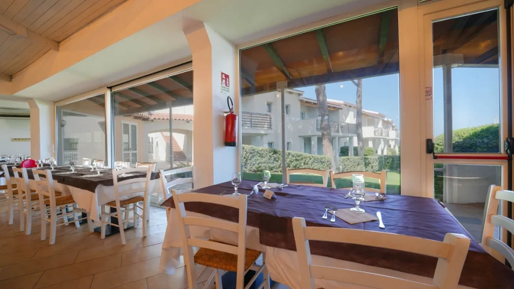 Sala ristorante con tavoli apparecchiati e vista sul giardino