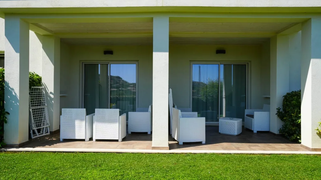 Terrazza con poltrone bianche e accesso alle camere sul giardino