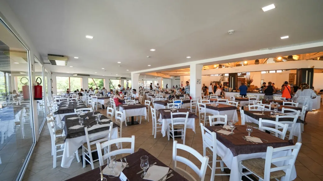 Ampia sala ristorante con tavoli apparecchiati e ospiti al buffet
