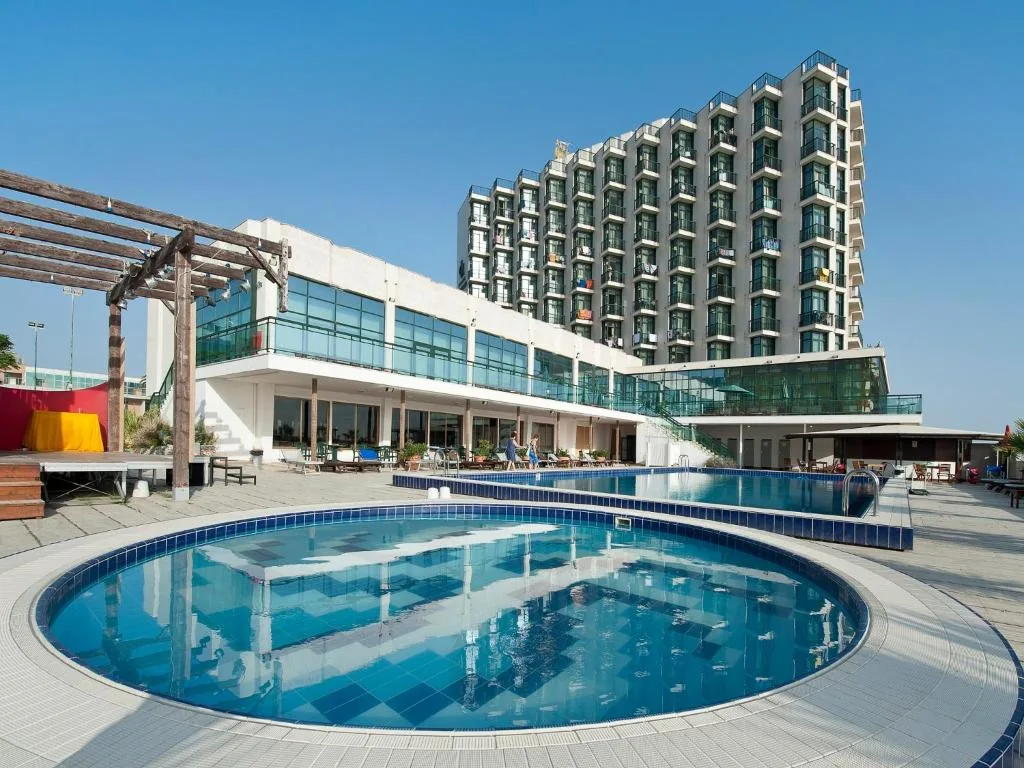 Ampia piscina esterna con vasca rotonda e area relax accanto all'edificio dell'hotel