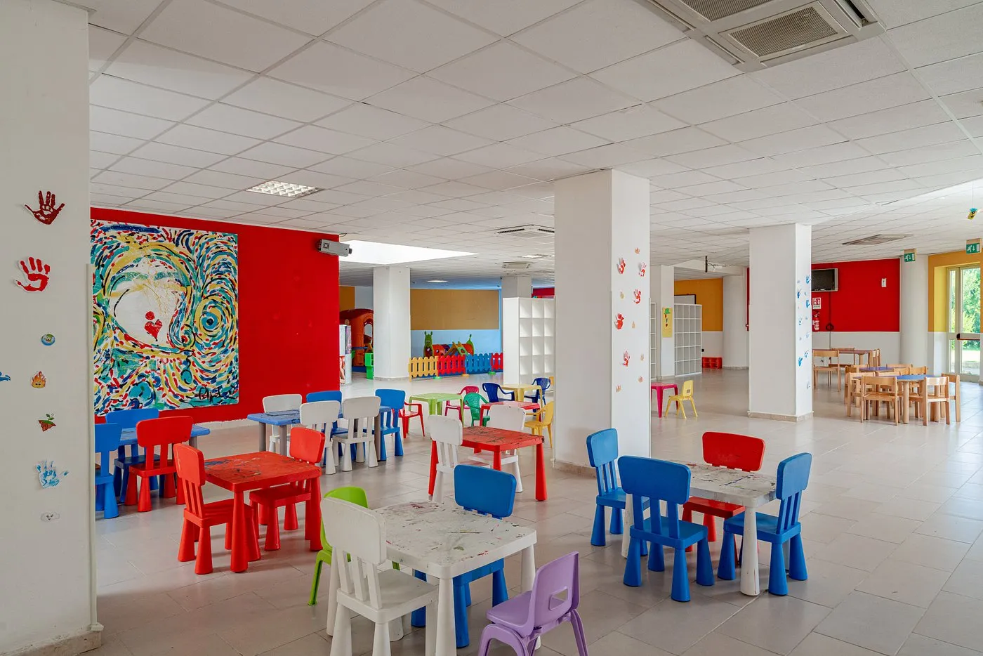 Sala giochi per bambini con tavoli e sedie colorate e pareti decorate