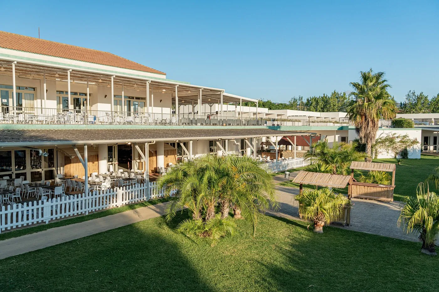 Esterno dell'edificio principale del resort con ristorante e giardino con palme