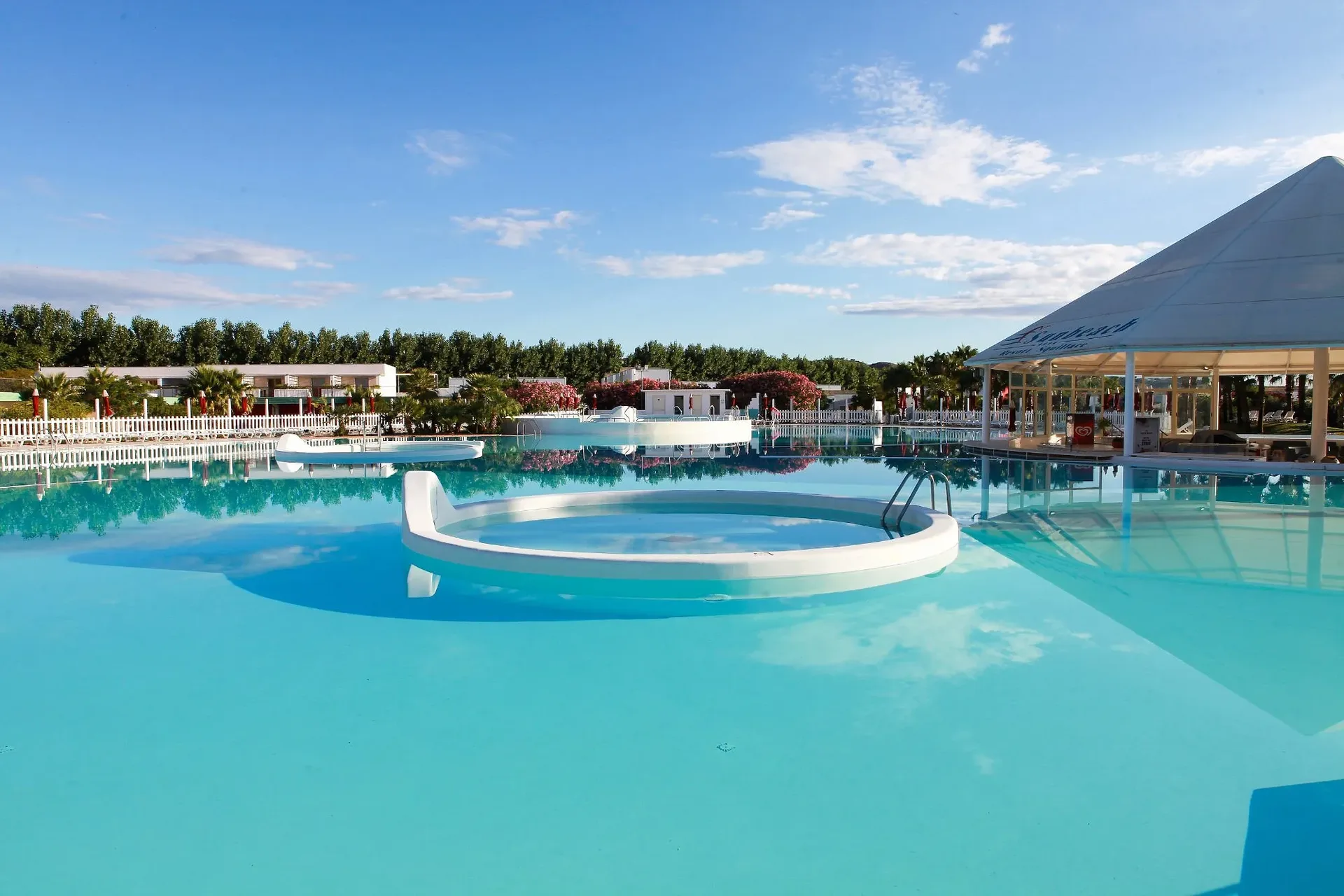 Piscina con vasche idromassaggio circolari e gazebo bianco sotto cielo azzurro