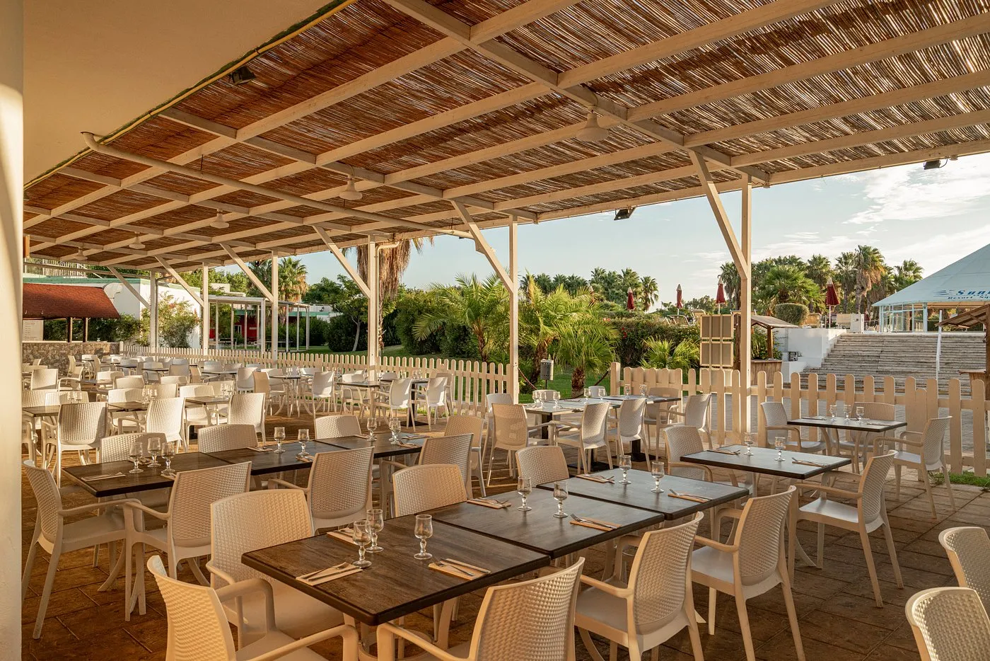 Terrazza ristorante all'aperto con copertura in canniccio e tavoli apparecchiati