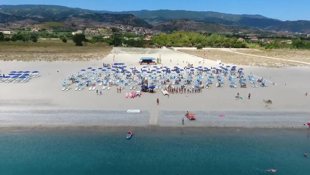 Vista aerea della spiaggia con ombrelloni blu e bagnanti