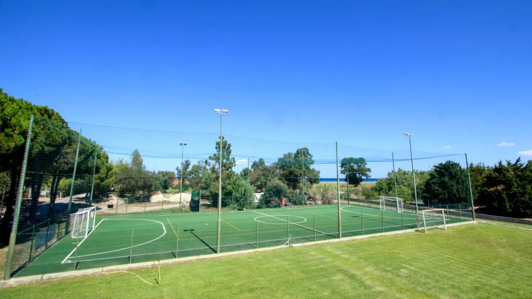 Campo sportivo in erba sintetica con porte da calcio e mare sullo sfondo