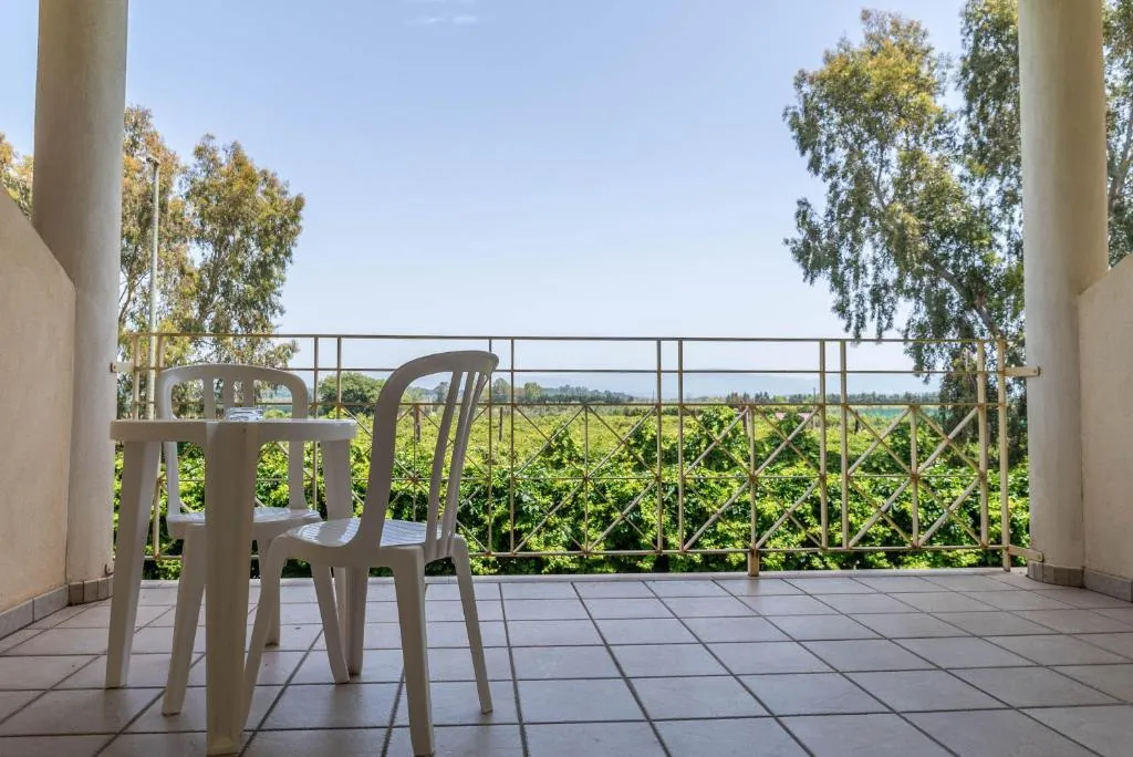 Balcone con tavolino e sedie bianche affacciato sul verde