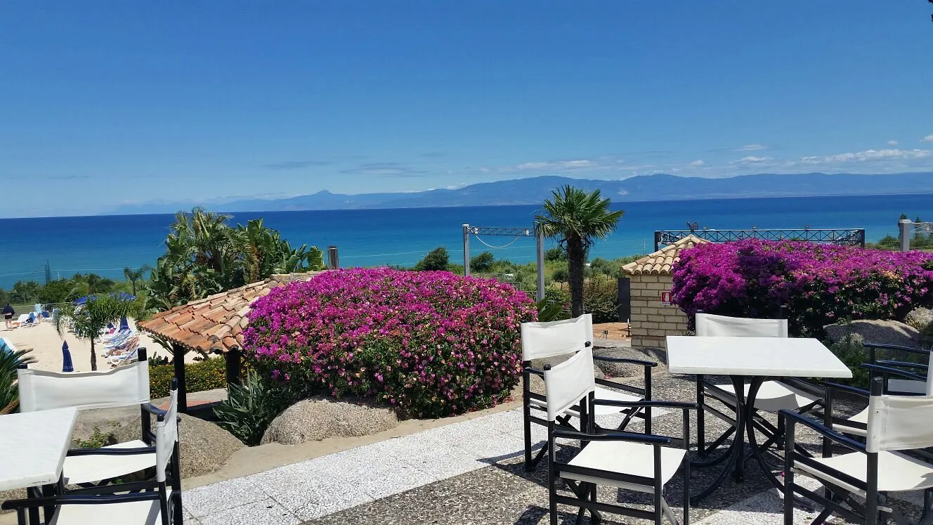 Terrazza fiorita con tavoli e vista sul mare e sulle montagne