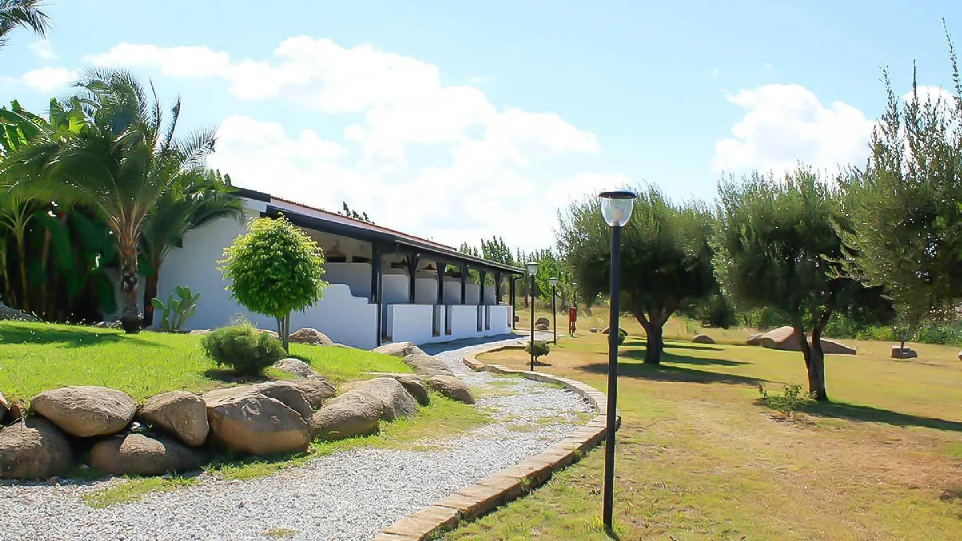 Edificio bianco con portico immerso nel giardino con ulivi