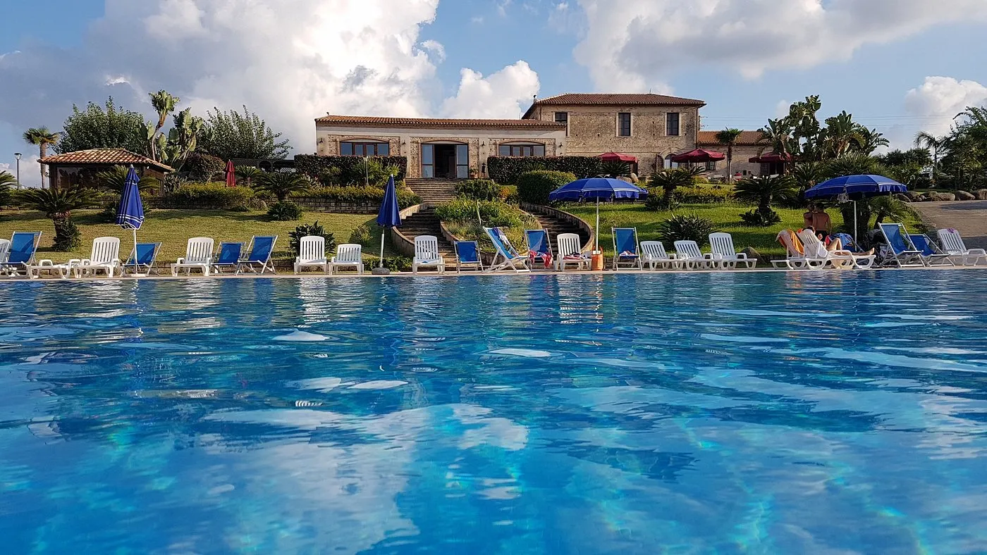 Piscina con lettini e casale in pietra sullo sfondo