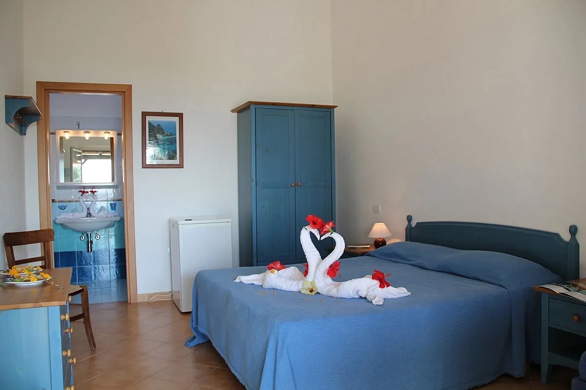 Camera matrimoniale con copriletto azzurro, armadio blu e bagno privato