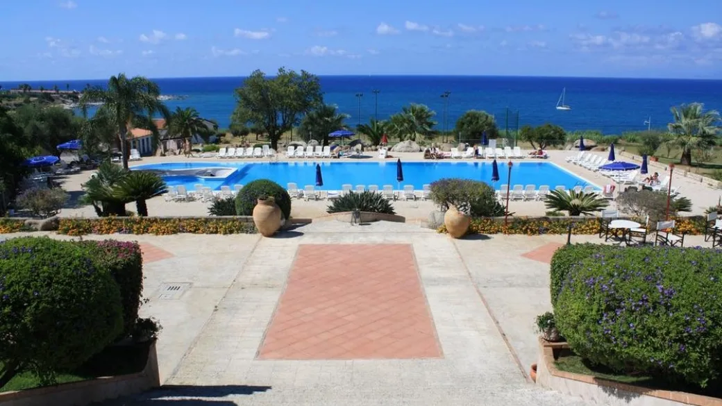 Vista panoramica della piscina e del mare dalla terrazza con vasi in terracotta