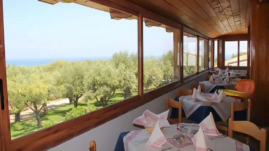 Sala ristorante con vetrate affacciate su uliveto e mare