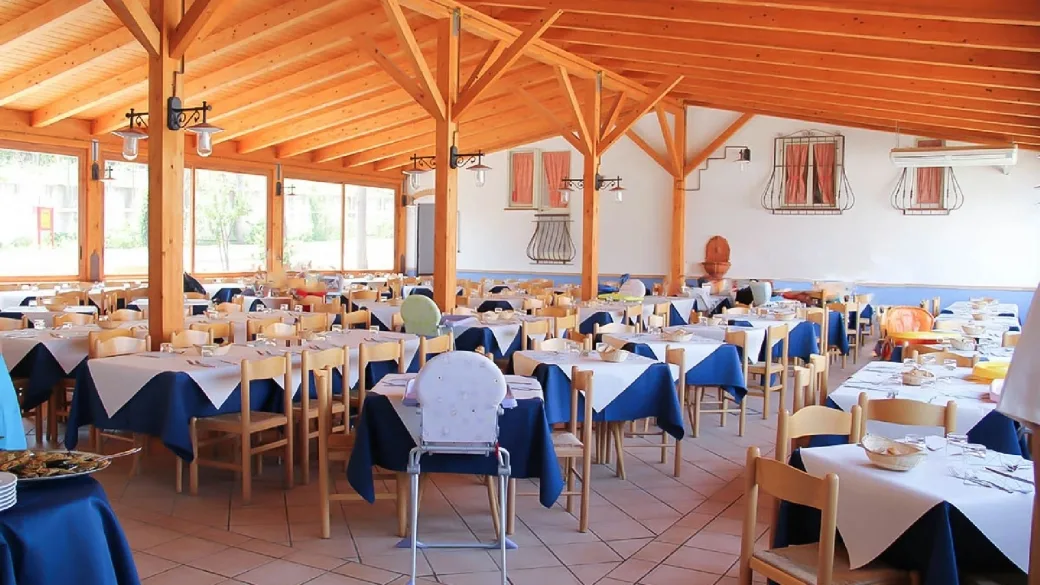 Ampia sala ristorante interna con tavoli apparecchiati e tovaglie blu