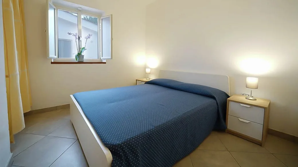 Camera matrimoniale luminosa con letto e comodini moderni