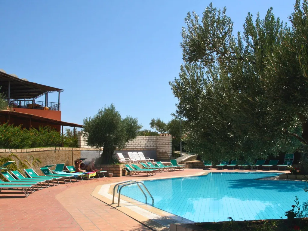 Piscina con lettini verdi, ulivi e terrazza sullo sfondo