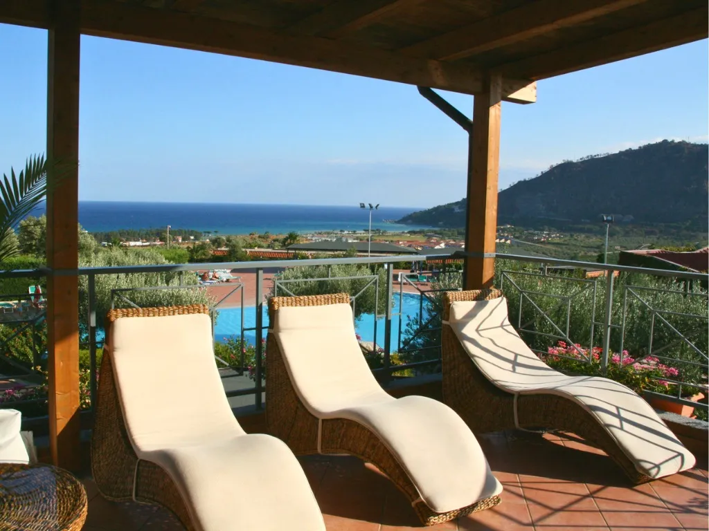Terrazza con lettini in vimini e vista panoramica su piscina e mare