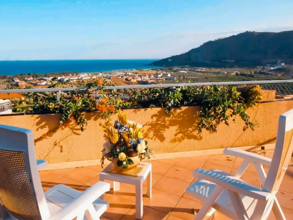 Terrazza con sedie bianche e vista panoramica sul mare al tramonto