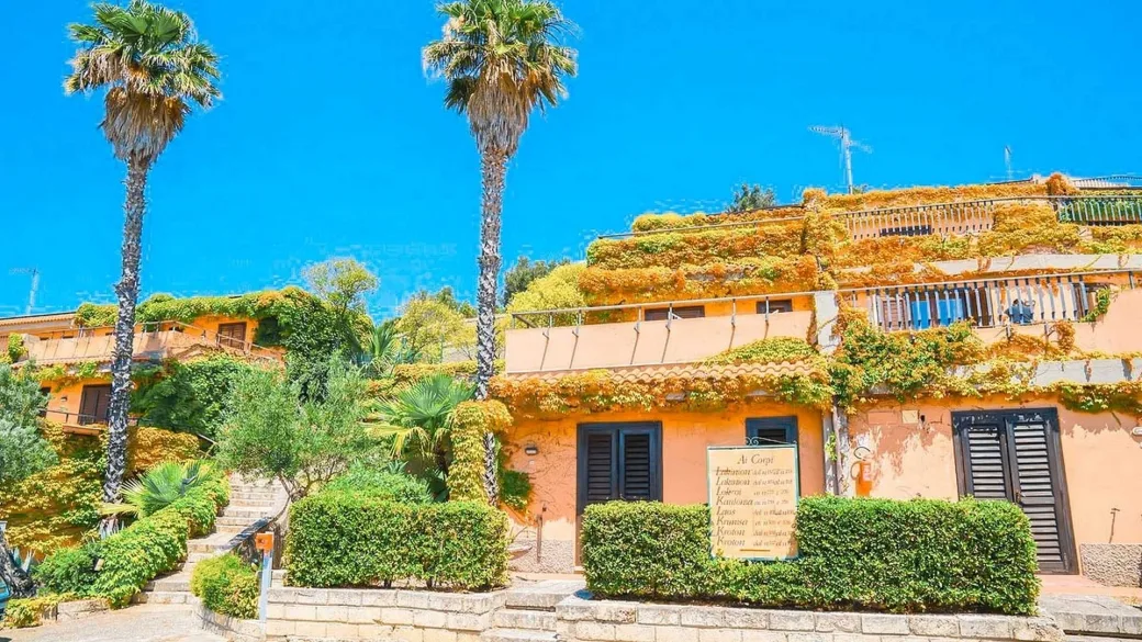 Edifici color arancione con palme e vegetazione rampicante