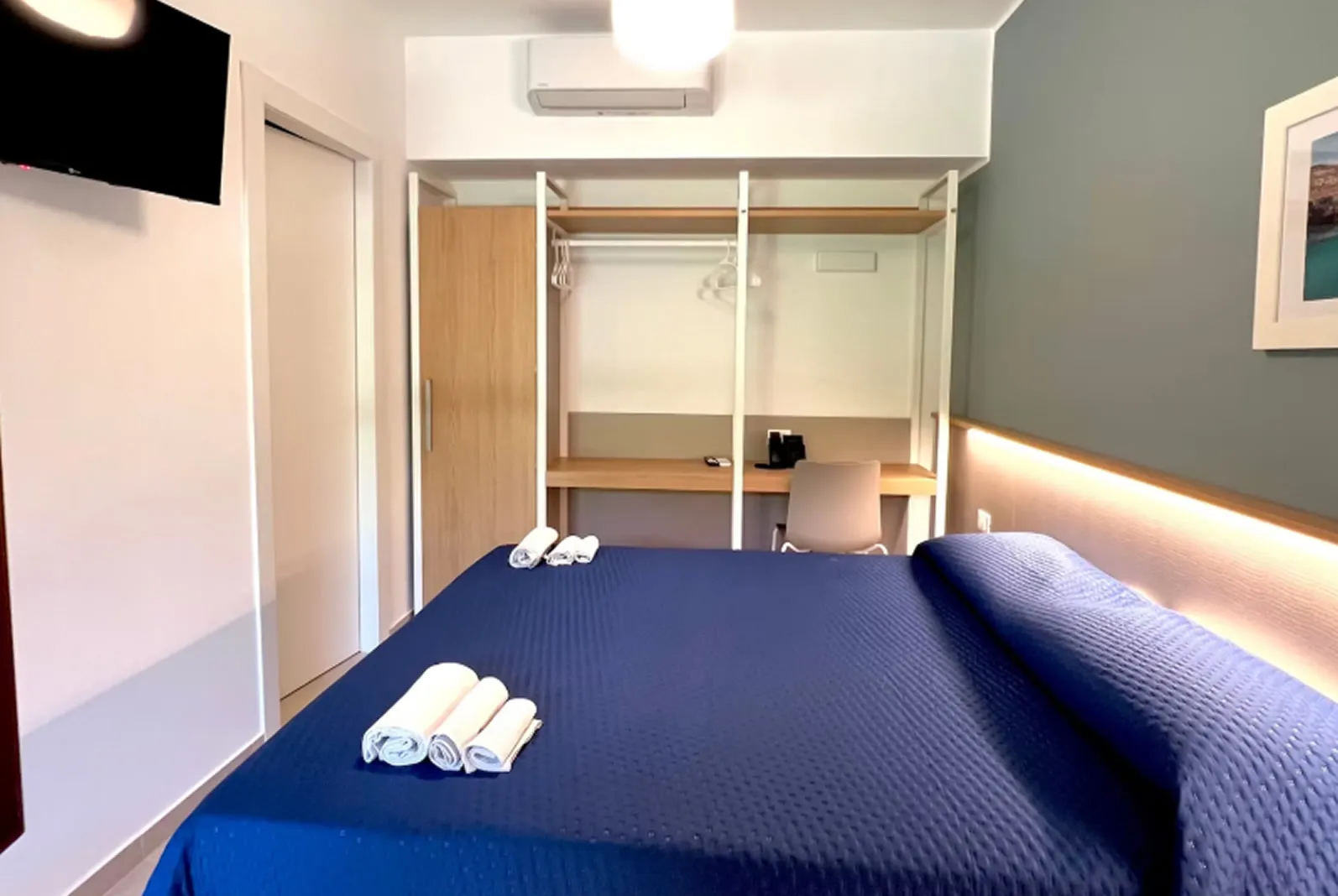 Camera moderna con letto matrimoniale, scrivania e TV a parete