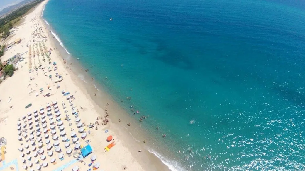Vista aerea della lunga spiaggia dorata bagnata dal mare blu intenso