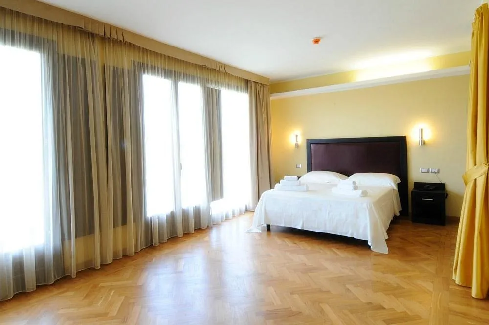 Ampia camera luminosa con letto matrimoniale, grandi finestre e parquet