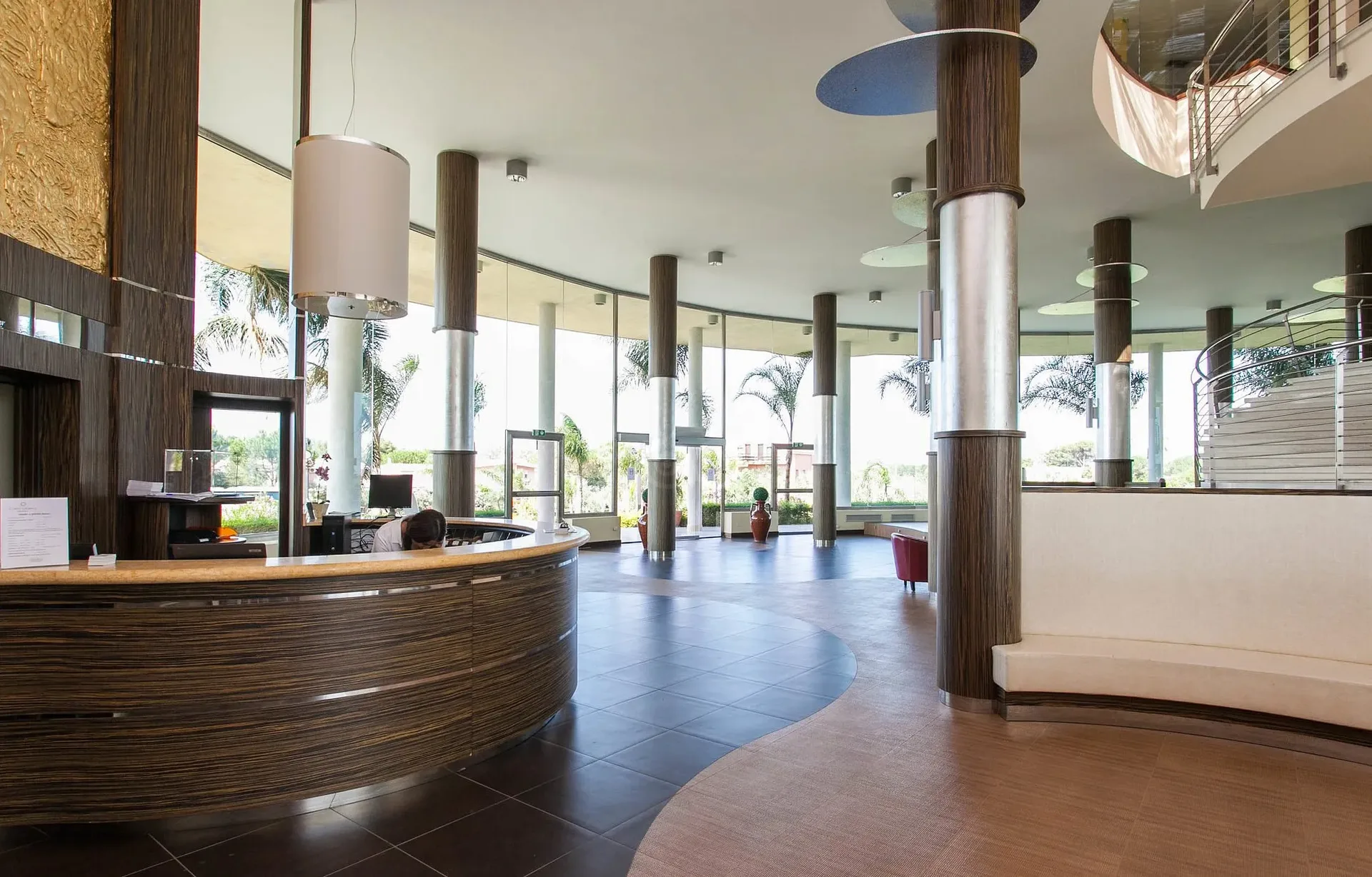 Hall del resort con reception curva in legno, colonne e ampie vetrate