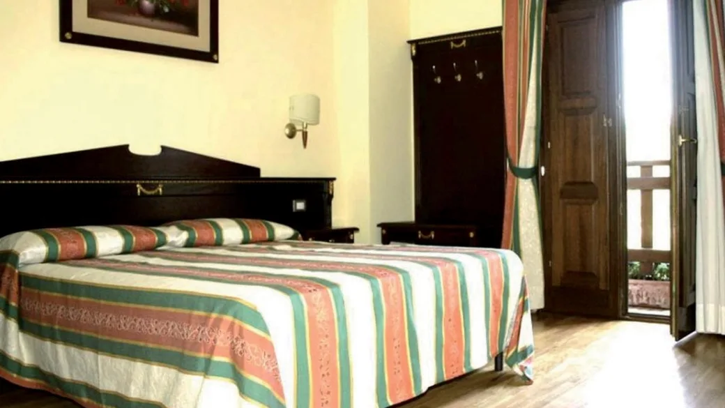 Camera con letto matrimoniale, copriletto a righe e uscita sul balcone