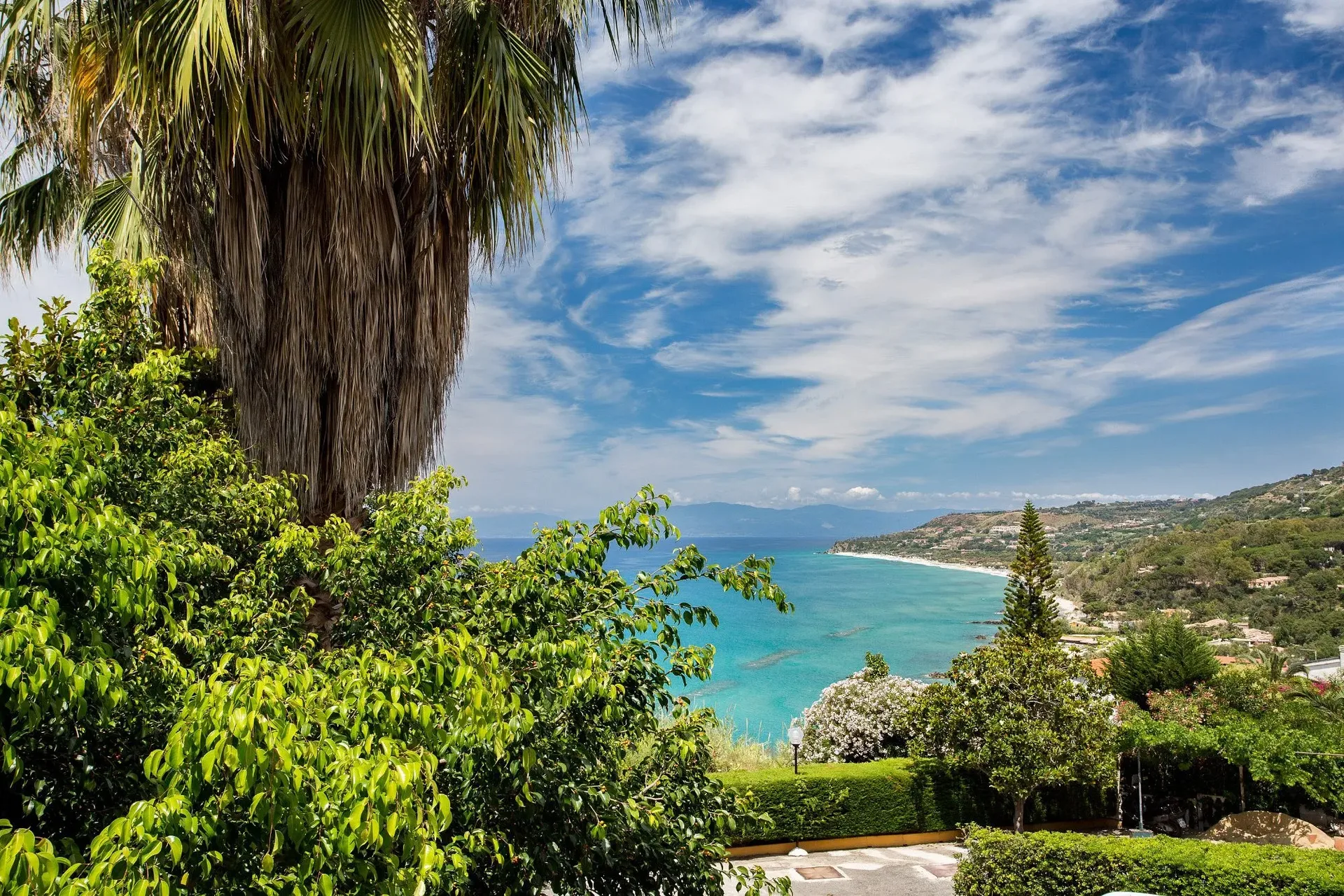 Vista panoramica del mare e della costa incorniciata da palme e vegetazione