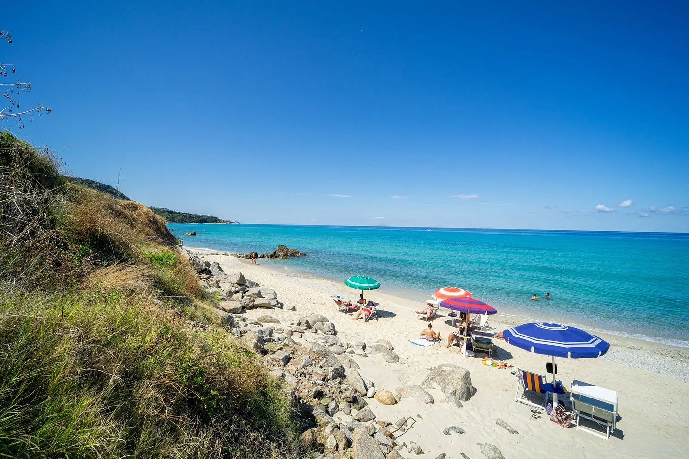 Spiaggia sabbiosa con ombrelloni e bagnanti lungo la costa