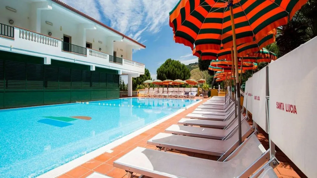 Lettini e ombrelloni a righe lungo la piscina dell'hotel Santa Lucia