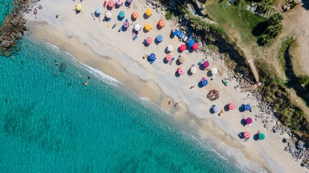 Vista aerea della spiaggia con ombrelloni colorati e mare turchese
