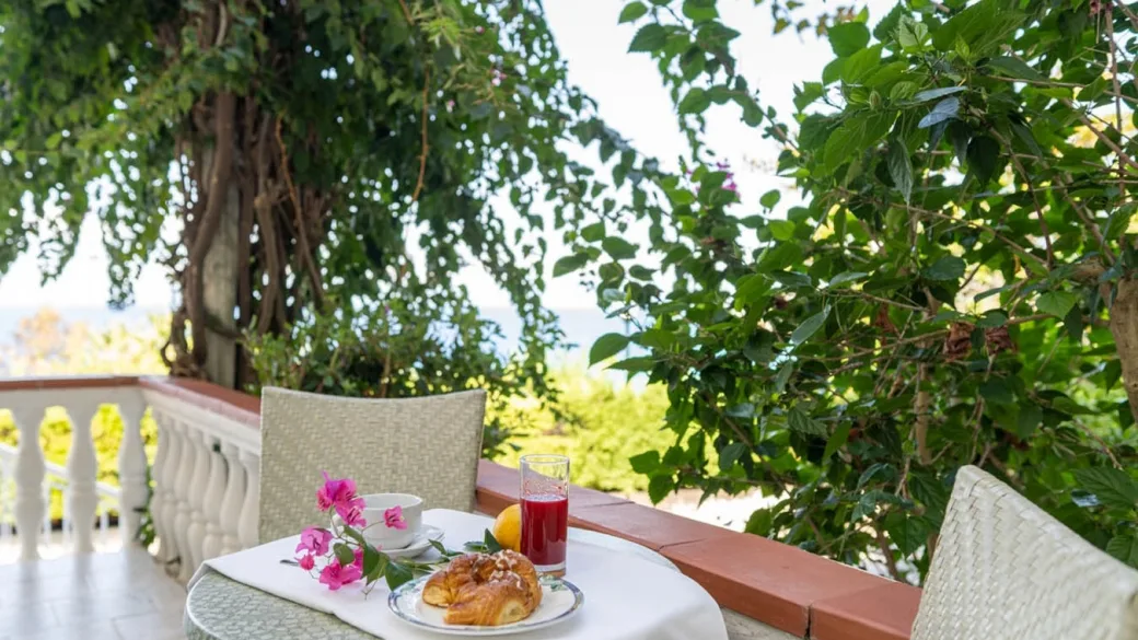 Colazione su tavolo in terrazza circondata da vegetazione e fiori