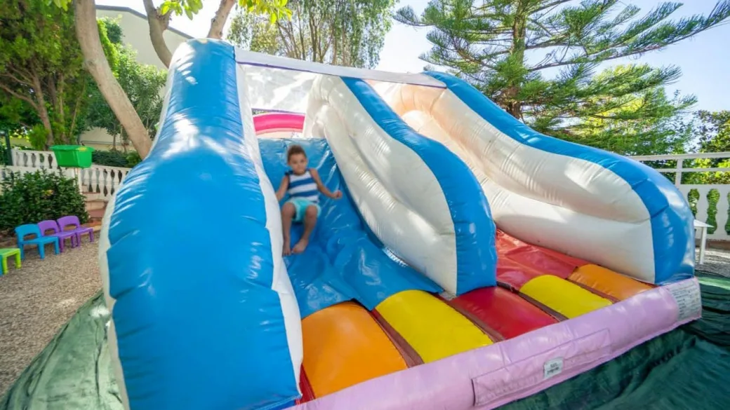 Bambino su scivolo gonfiabile colorato nell'area giochi