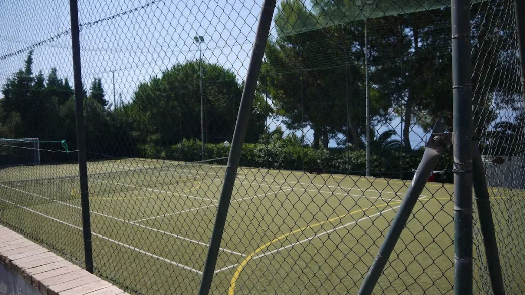 Campo sportivo in erba sintetica visto attraverso la recinzione