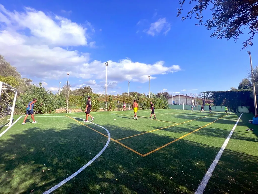 Campo da calcetto in erba sintetica con giocatori e cielo azzurro