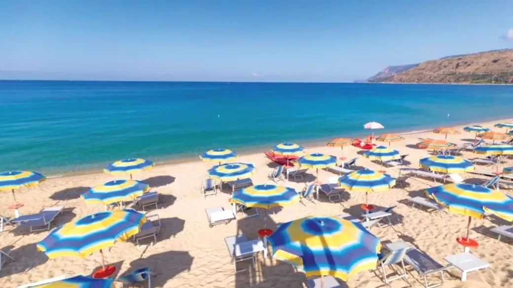 Vista aerea della spiaggia con ombrelloni colorati, mare turchese e costa