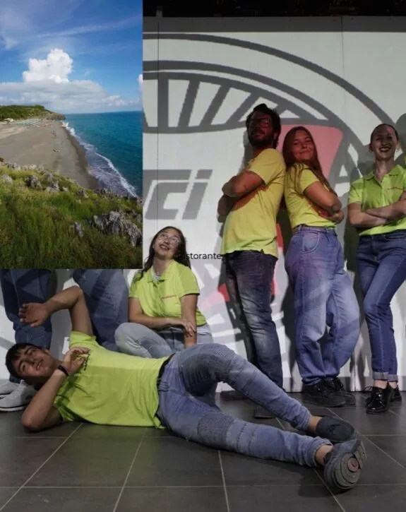 Gruppo di giovani con magliette gialle sorridenti, posano davanti a un grande schermo, accanto a un paesaggio marino.