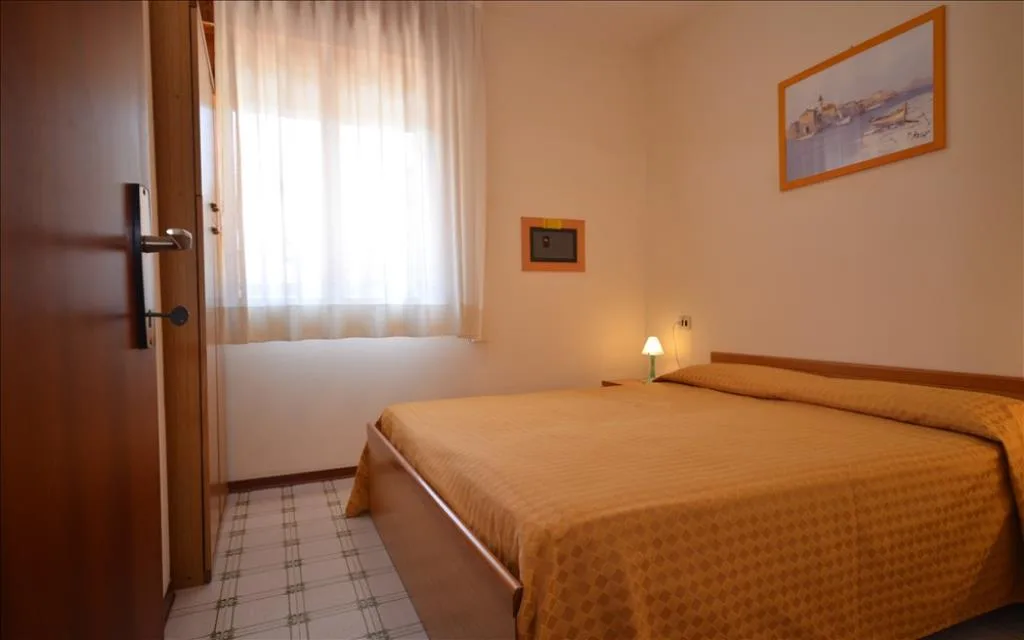 Camera matrimoniale con letto, finestra luminosa e lampada da comodino