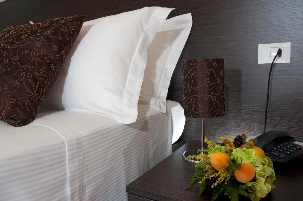 Dettaglio di letto con cuscini, lampada da comodino e composizione di frutta