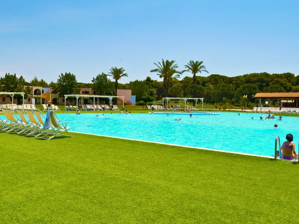Piscina del resort con lettini prendisole e palme sullo sfondo