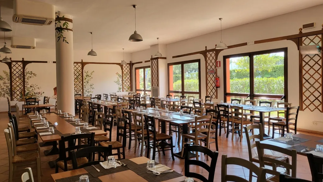 Sala ristorante interna luminosa con tavoli in legno e decorazioni a grigliato