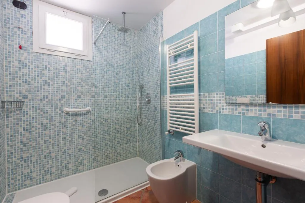 Bagno con doccia, mosaico azzurro, lavabo e bidet