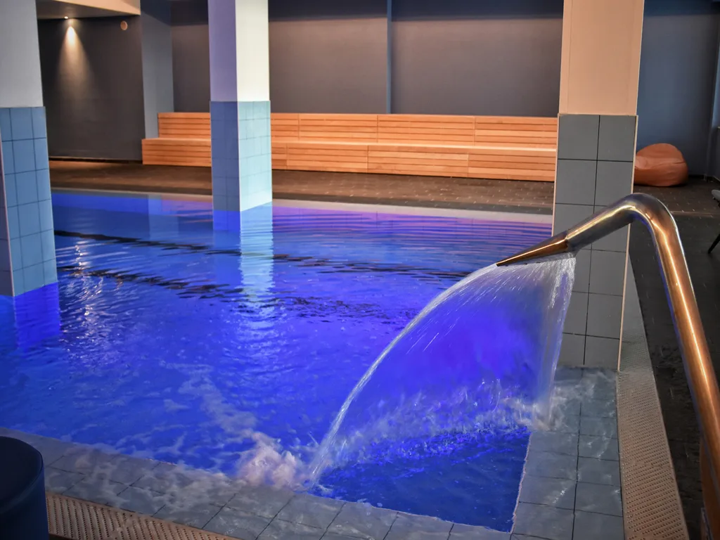 Piscina interna riscaldata con cascata d'acqua e illuminazione blu