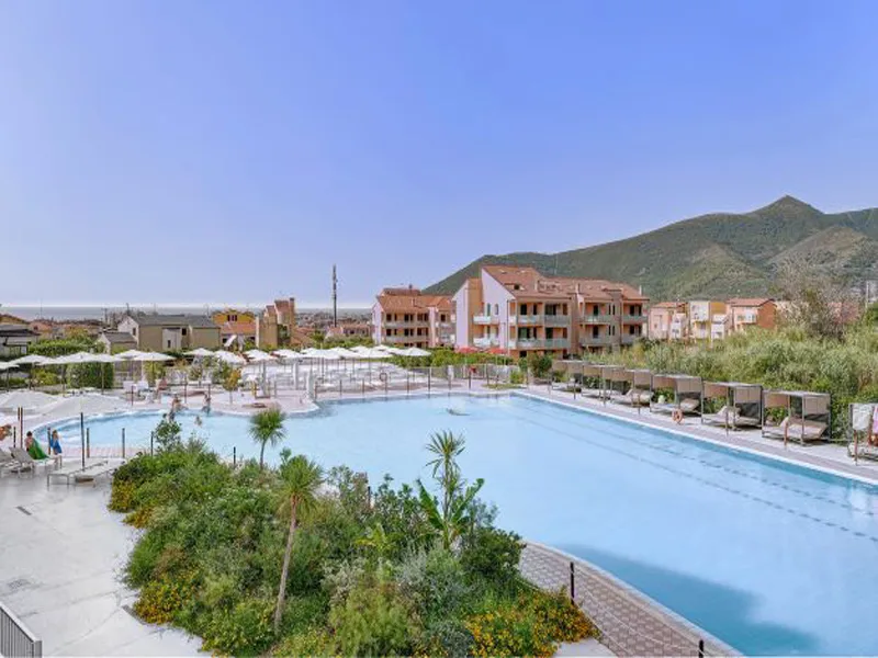 Ampia piscina del resort circondata da vegetazione e lettini