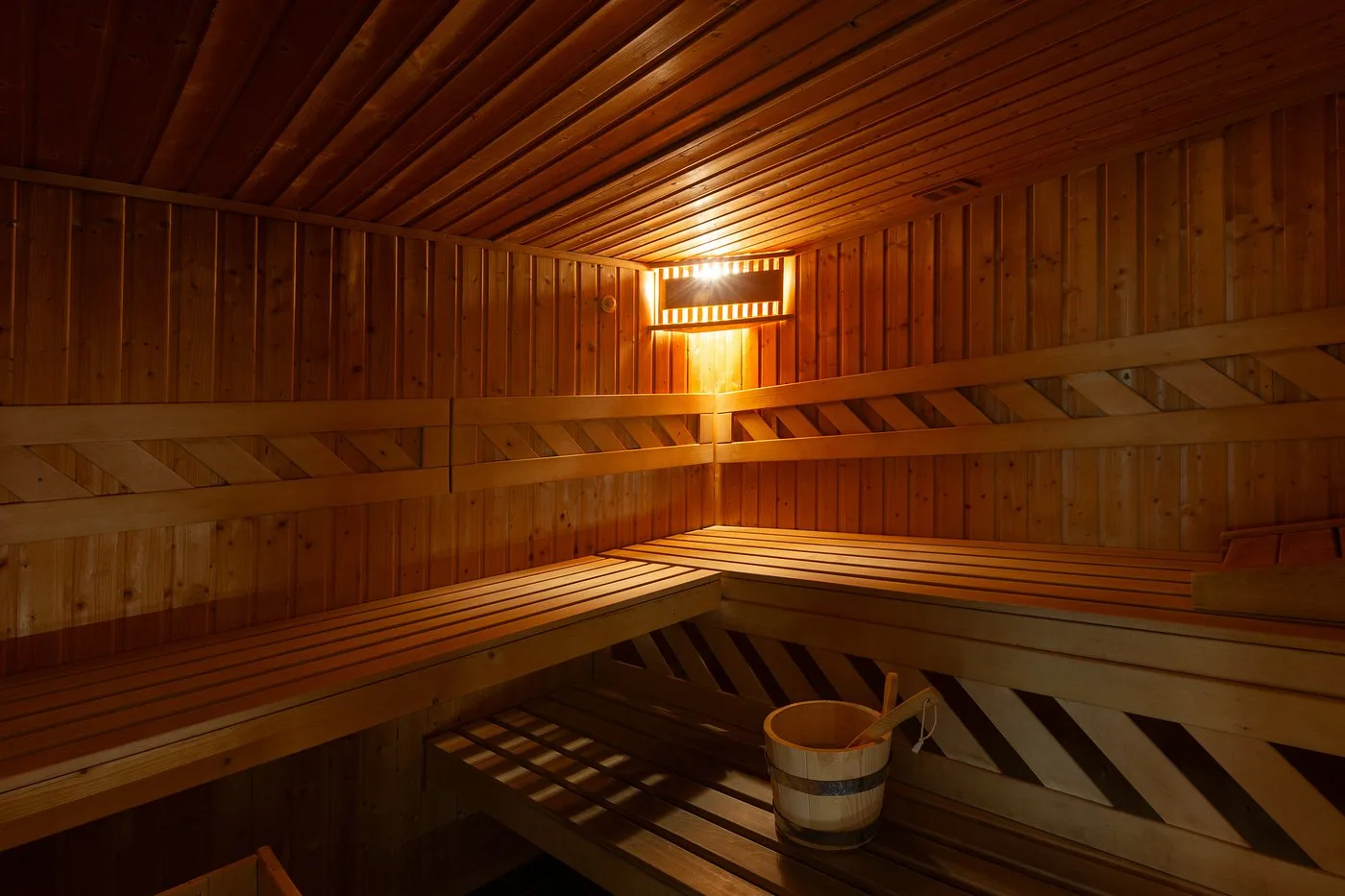 Interno di sauna finlandese in legno con panche e secchiello tradizionale