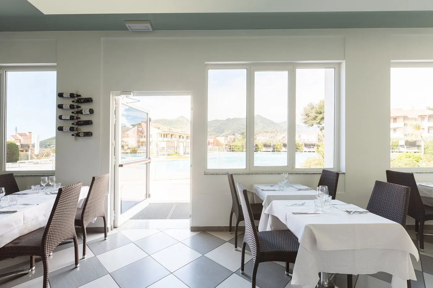 Sala ristorante luminosa con tavoli apparecchiati e vista sulla piscina e sulle colline
