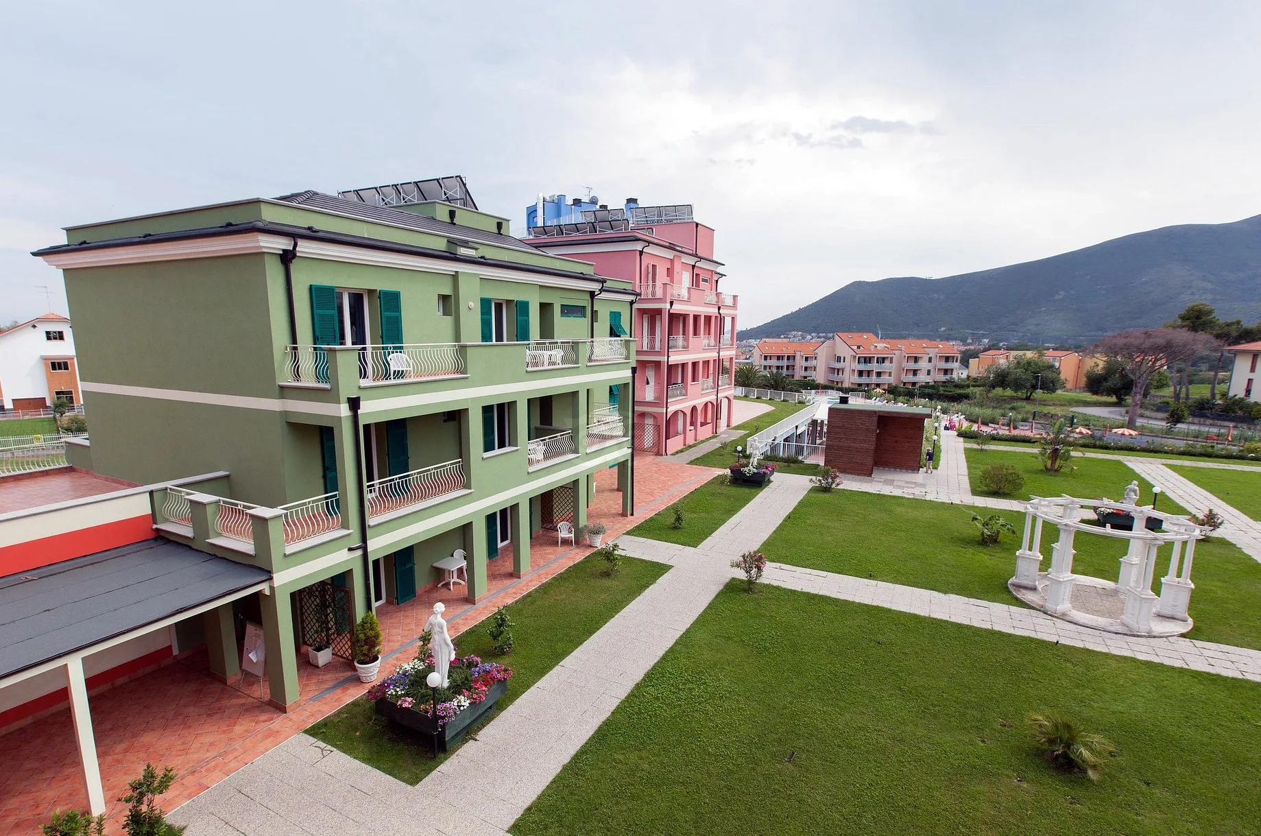 Vista esterna degli edifici colorati del resort con giardino, statue e gazebo bianco