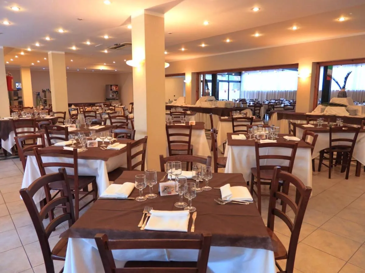Sala ristorante interna con tavoli apparecchiati, tovaglie bianche e sedie in legno