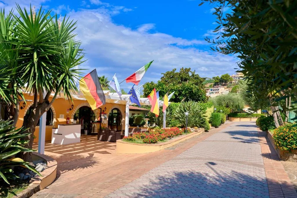 Vialetto del villaggio con palme, bandiere e ingresso della reception